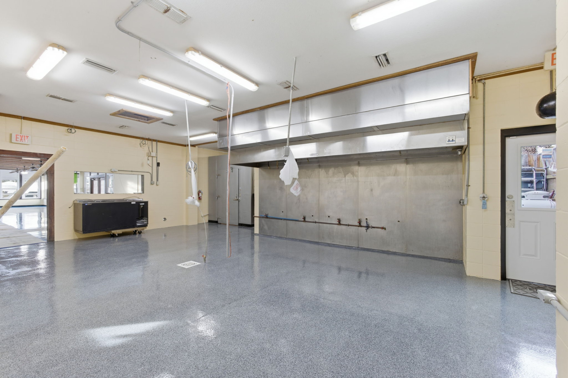 Empty commercial prep space with hood vent and polished floor