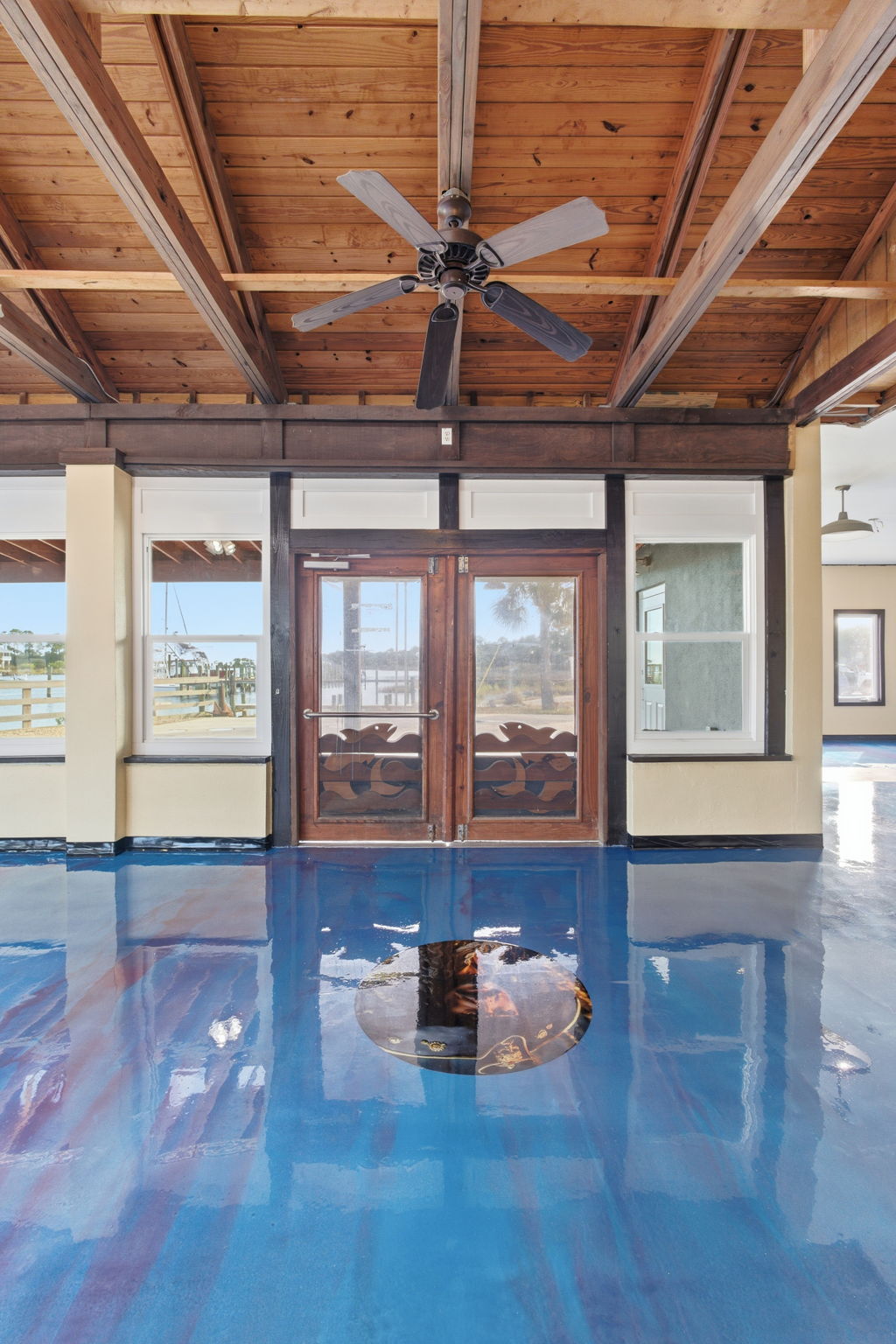 Open commercial space with blue epoxy floor and wood beam ceiling